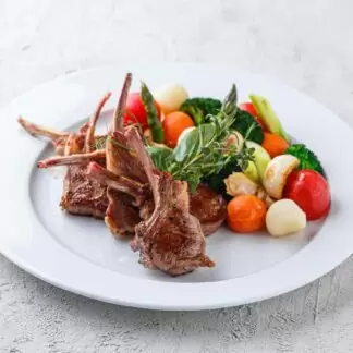 Каре молодого  новозеланського ягняти з італійськими травами, обпаленими овочами під сирним соусом