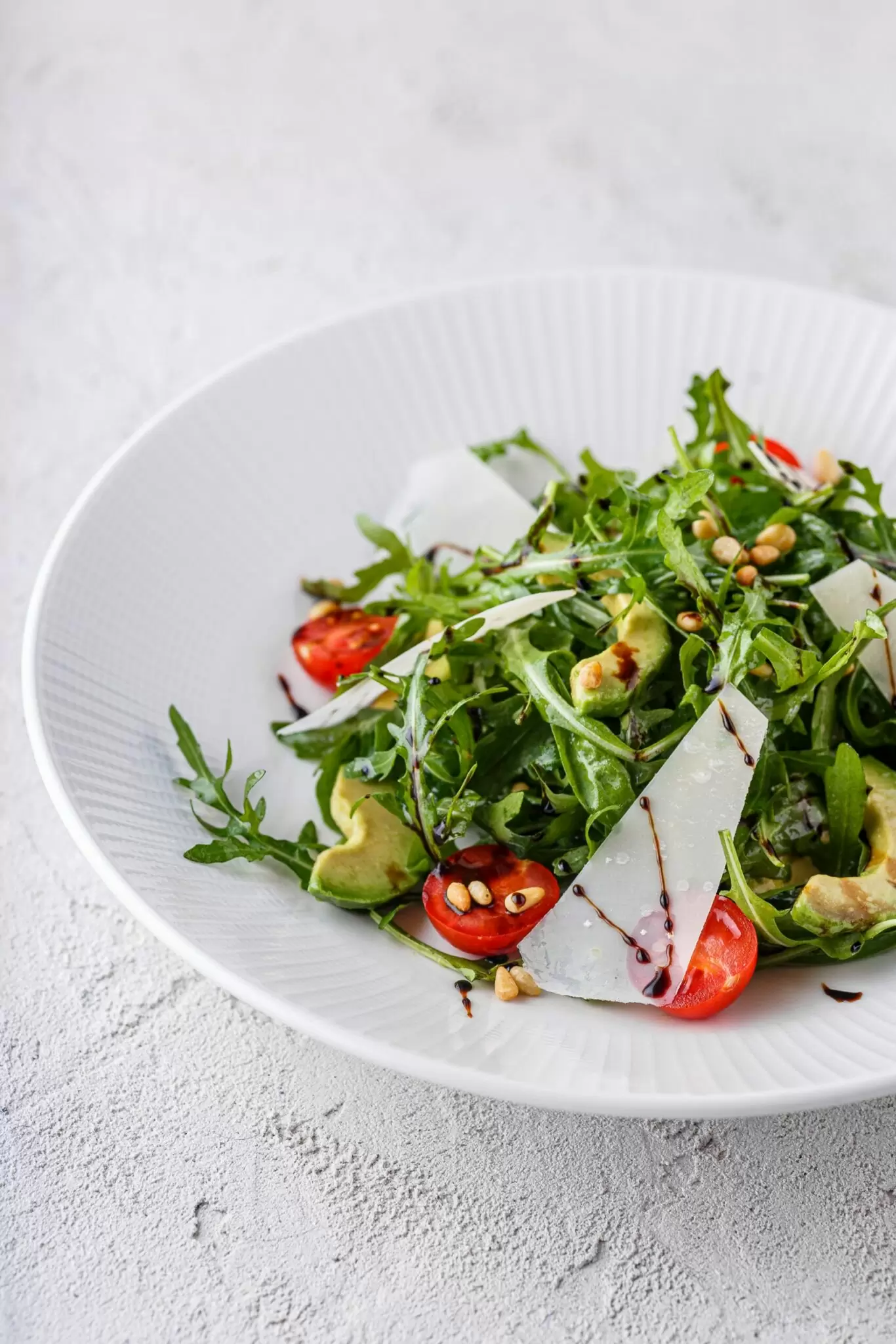 Салат із хрусткої руколи з томатами чері, пармезаном, авокадо, кедровими горіхами і соусом Цітронет